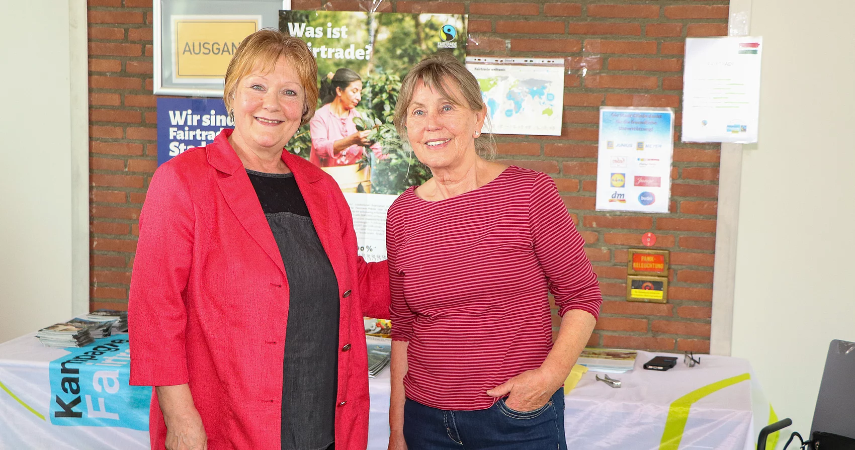 Zwei Frauen lächeln an einem Fairtrade-Informationsstand.