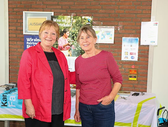 Zwei Frauen lächeln an einem Fairtrade-Informationsstand.