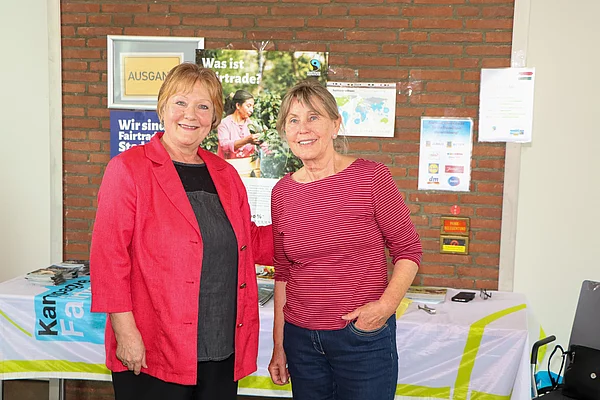 Zwei Frauen lächeln an einem Fairtrade-Informationsstand.