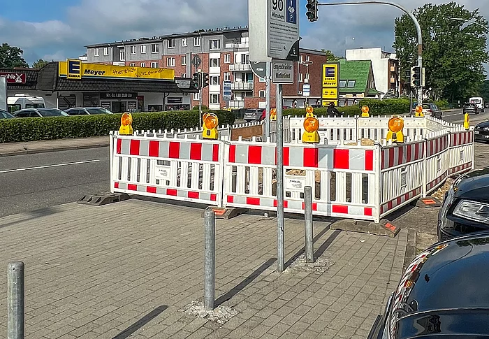 Auf einem Gehweg ist eine rot-weiße Baustellen-Absperrung aufgebaut.