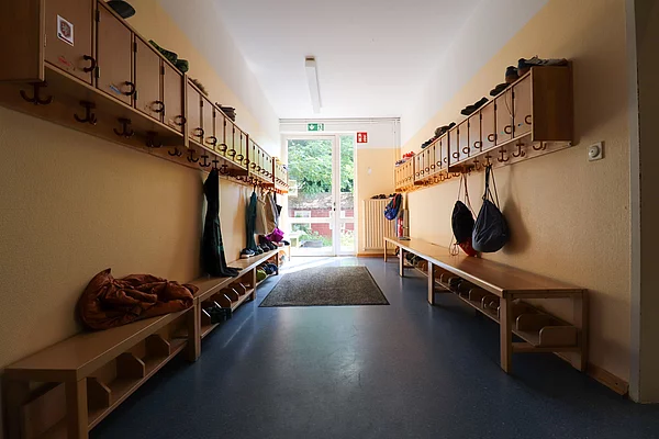 Ein Flur im Hort mit Garderobenhaken und kleinen Boxen darüber. 
