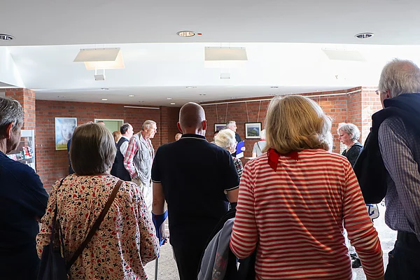 Eine Menschengruppe schaut auf Fotos.