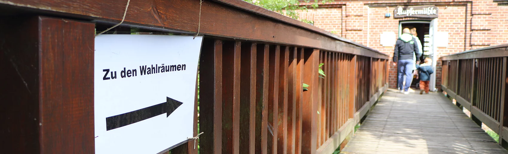 Die Brücke zur Kupfermühle in Glinde mit einem Schild auf dem steht "Zu den Wahlräumen"