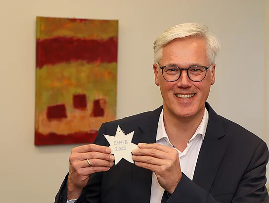 Bürgermeister Rainhard Zug hält einen Stern mit dem Segensspruch 2025 der Sternsinger in einer Hand.