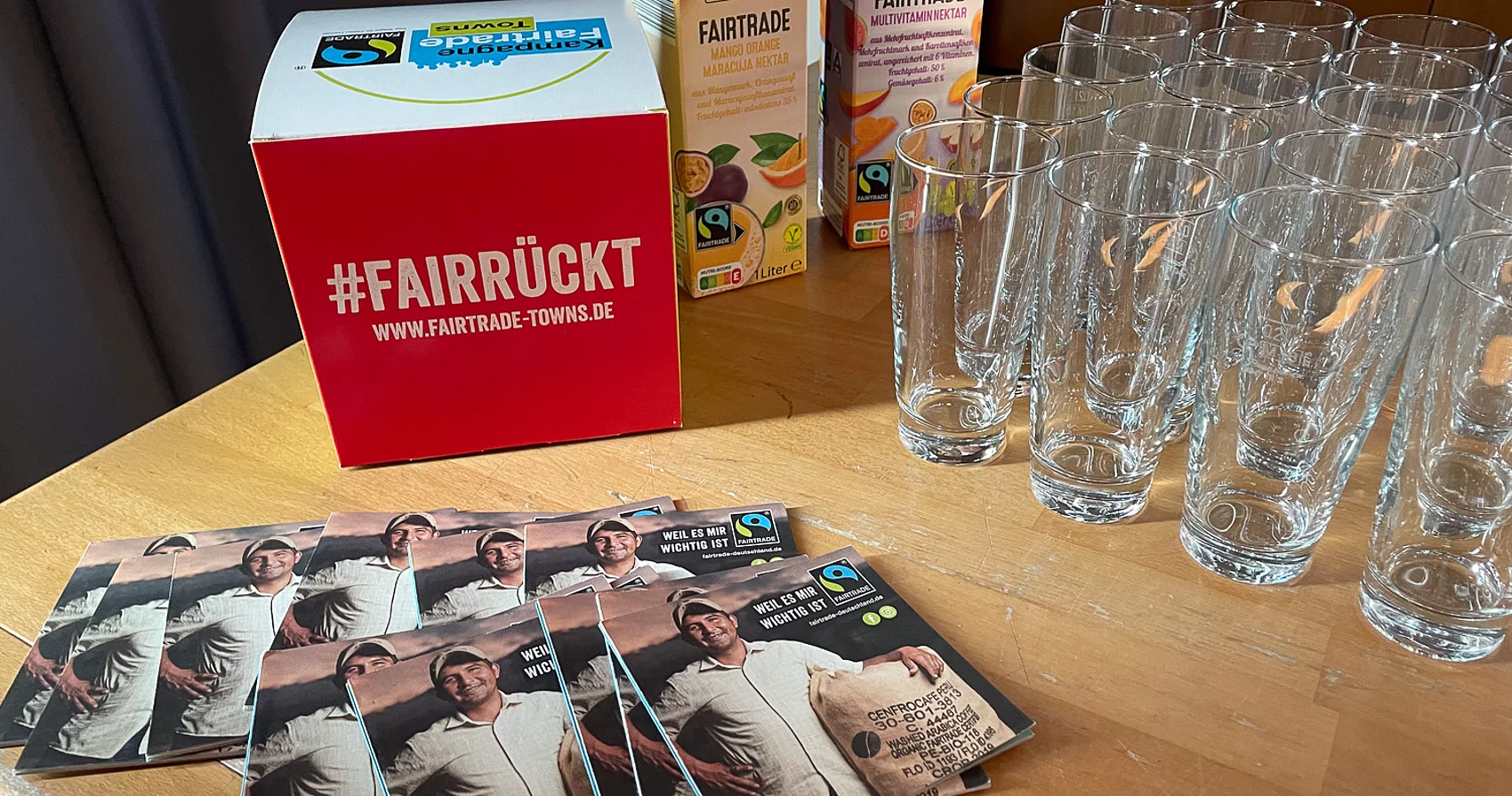 Auf einem Tisch liegen Fairtrade-Flyer und es steht Fairtrade-Saft neben Gläsern.