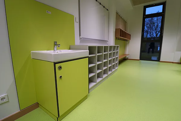 Ein kleines Handwaschbecken und ein Regal in einem Klassenraum.