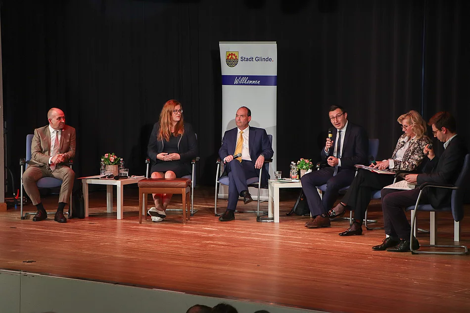 Menschen sitzen auf Stühlen auf einer Bühne