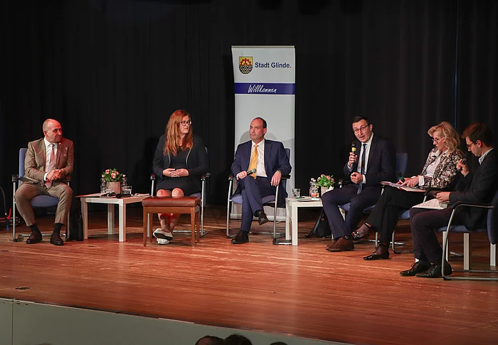 Menschen sitzen auf Stühlen auf einer Bühne