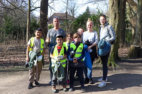 Erwachsene mit Kindern beim Müllsammeln