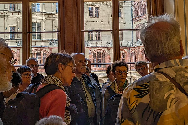 Menschen hören einer Museumsführerin zu.