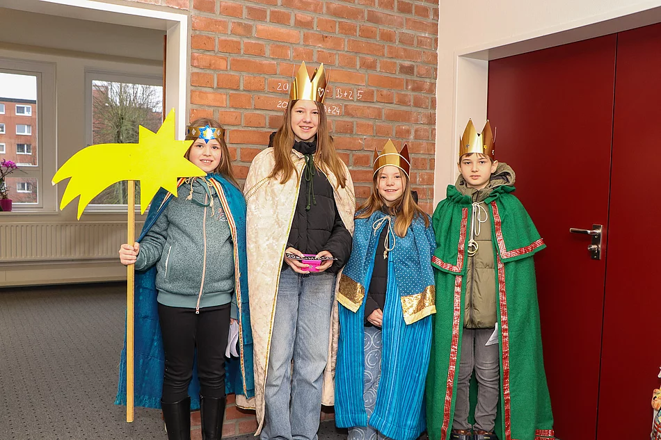 Drei Mädchen und ein Junge sind als Sternsinger verkleidet.