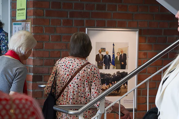 Besucher schauen auf ein Foto an der Wand im Treppenhaus.