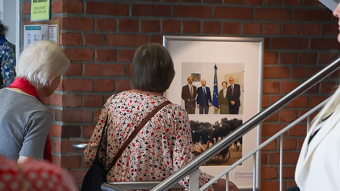 Besucher schauen auf ein Foto an der Wand im Treppenhaus.