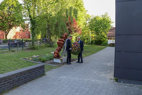 Bürgermeister und Bürgervorsteher legen einen Kranz an einem Mahnmal ab.