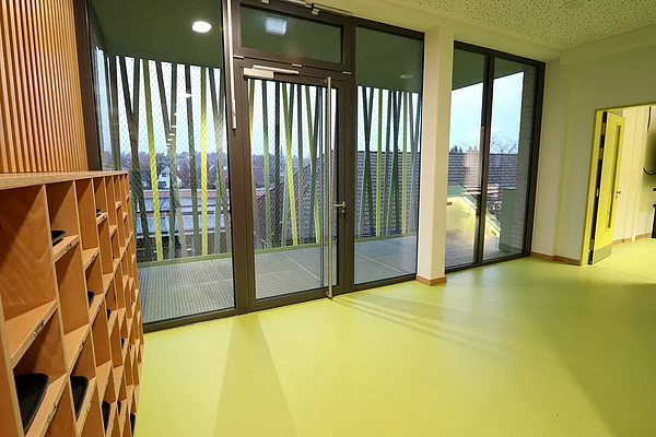 Blick von Innen auf die Außentreppe mit grünen, gelben Elementen.
