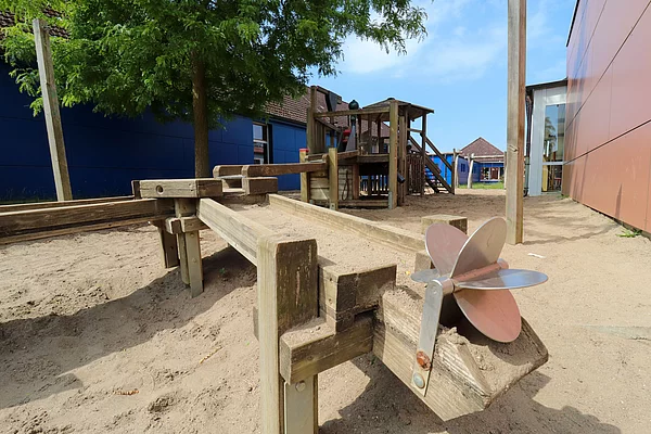 Spielplatz: Im Vordergrund ein Mühlenrad, das von Wasser angetrieben werden kann, hinten eine Wasserstrecke aus Holz gebaut.