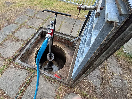 In Boden ist ein Loch aus dem Wasser mit einer Pumpe gefördert wird.