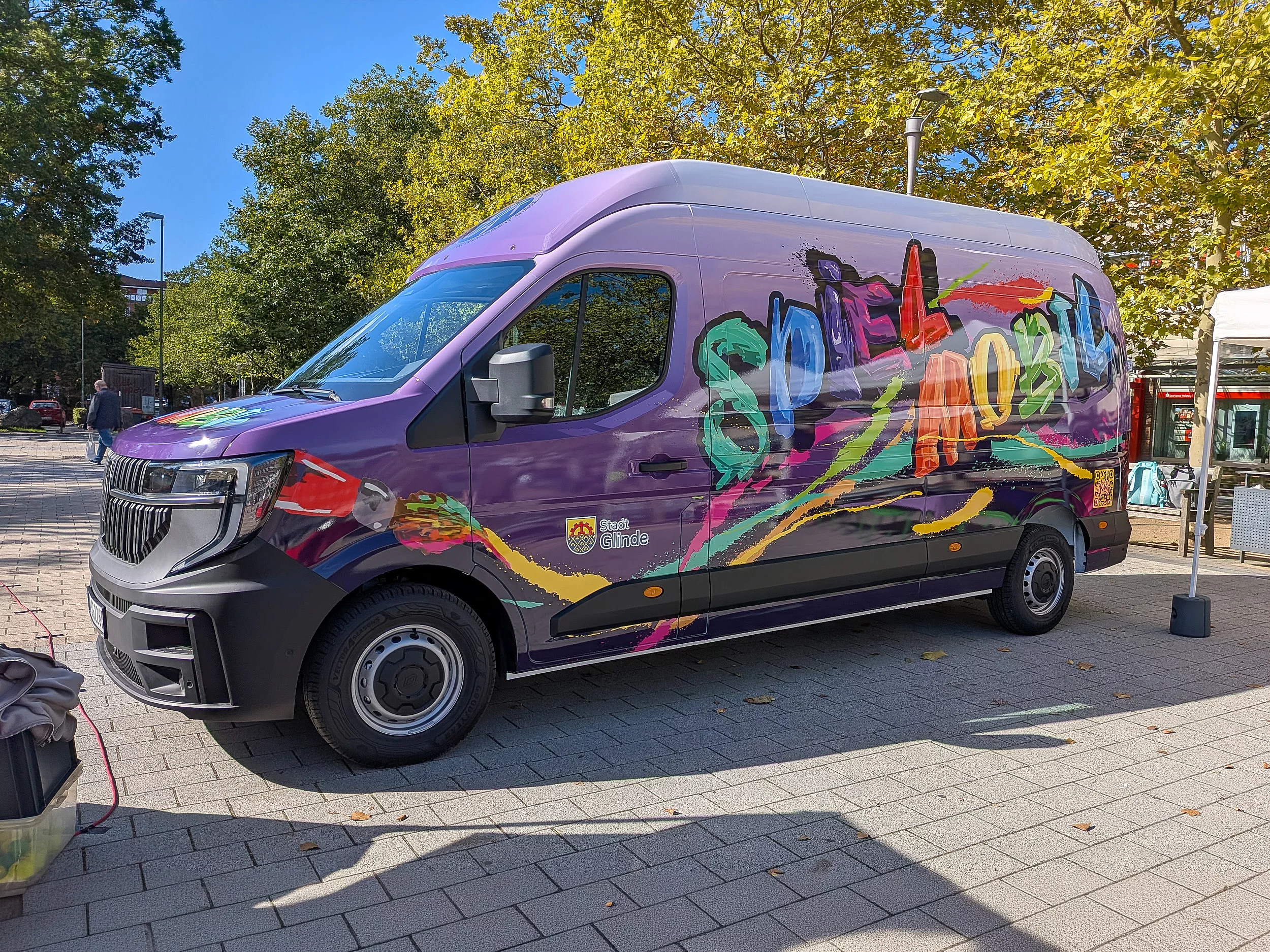 Ein buntbekleber Kleintransporter mit einer Graffiti-Aufschrift Spielmobil