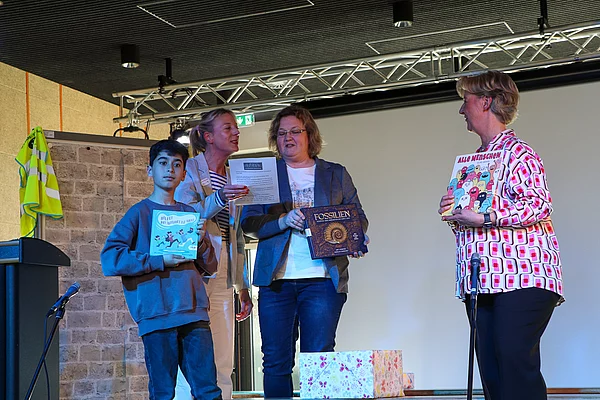 Zwei Frauen überreichen einem Jungen und Sabine Walther Bücher als Geschenk