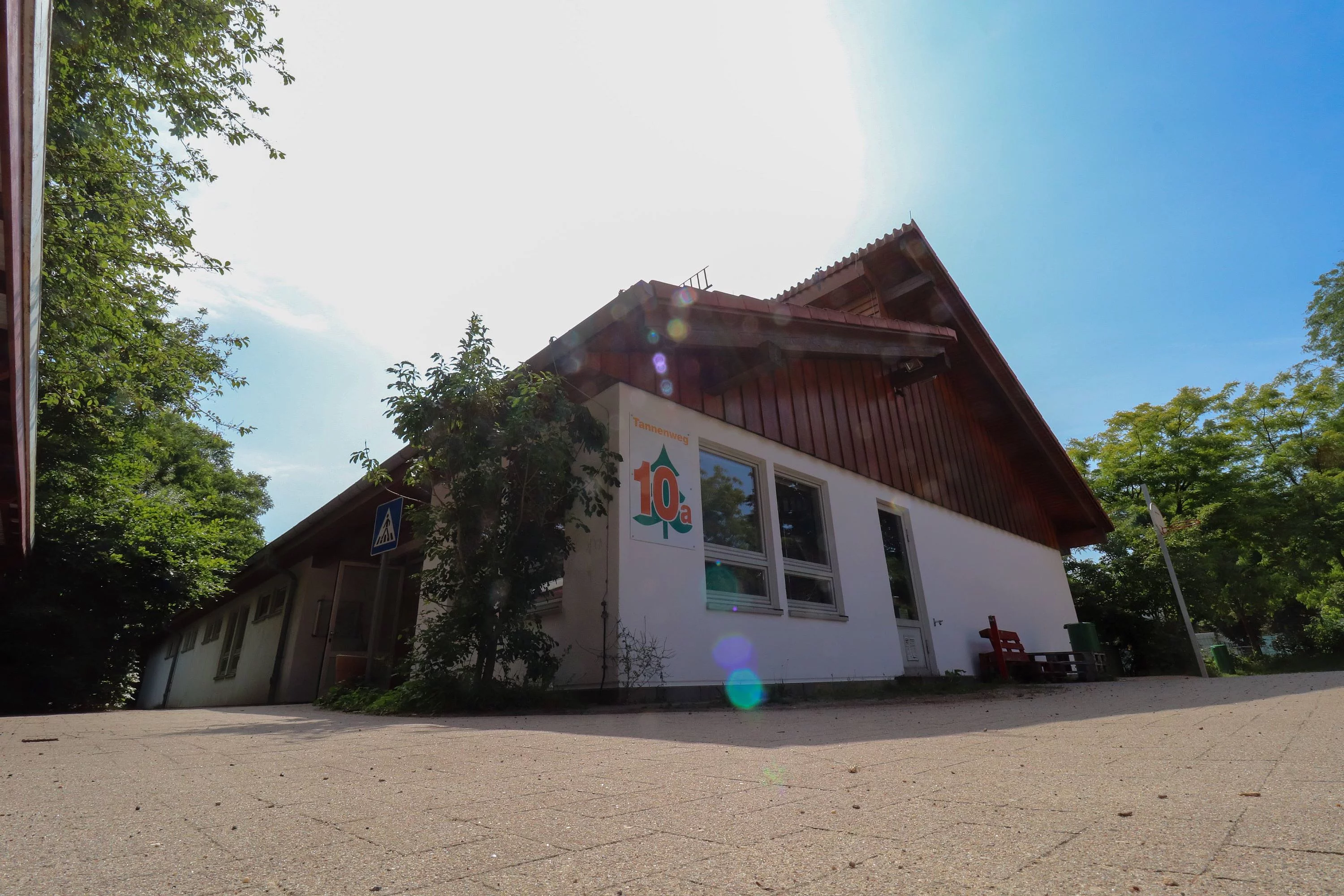 Das Hauptgebäude des Hort Löwenzahn - Außenstelle Tannenweg, weißes Haus mit braunem Spitzdach. 