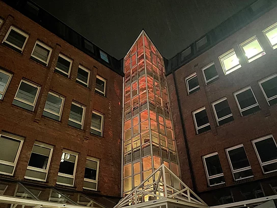 Das Treppenhaus des Glinder Rathauses leuchtet orange.