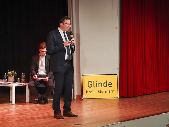 Patrik Klose steht auf der Bühne und hat ein Mikrofon in der Hand.