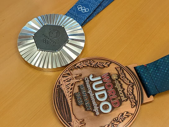 Eine olympische Silbermedaille und eine Bronzemedaille einer Weltmeisterschaft liegen auf einem Tisch.
