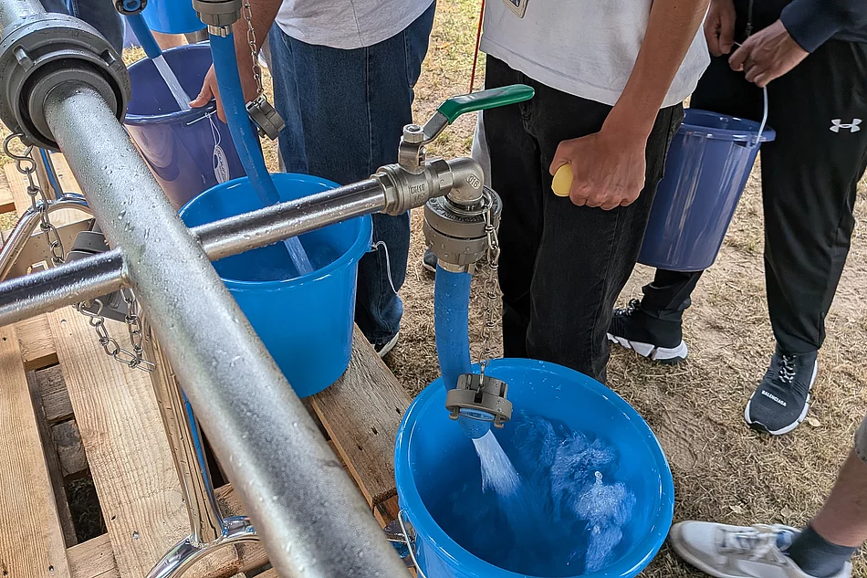 An einem Wasserhahn wird ein Eimer gefüllt.