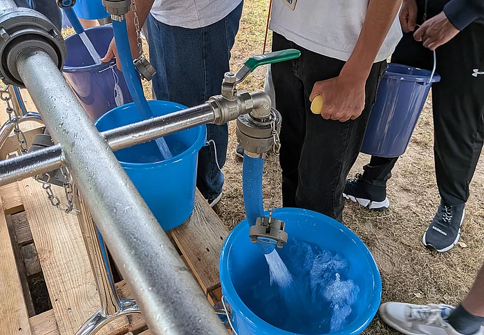 An einem Wasserhahn wird ein Eimer gefüllt.