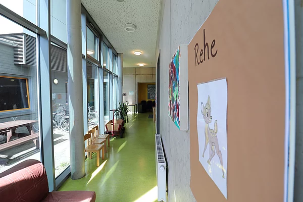 Ein Flur: Links bodentiefe Fenster, rechts eine Pinnwand