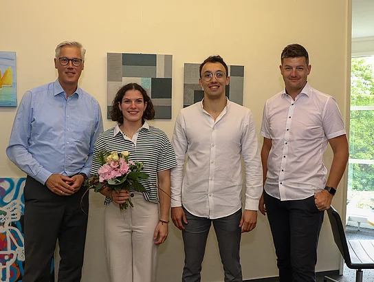 Vier Menschen stehen für ein Gruppenfoto zusammen.