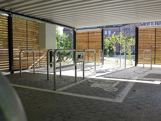 Im Inneren des Unterstandes sind Metallbügel im Boden verankert. An diesen können Fahrräder angeschlossen werden.