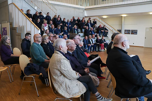 Auf einer Treppe und auf Stühlen sitzen Menschen