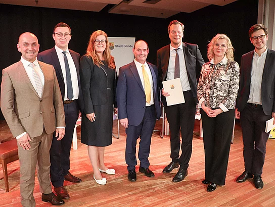 Gruppenfoto der Kandidatinnen und Kandidaten zur Wahl einer Bürgermeisterin/ eines Bürgermeisters mit Bürgervorsteher Claus Peters und Moderator Carl Schreiber.