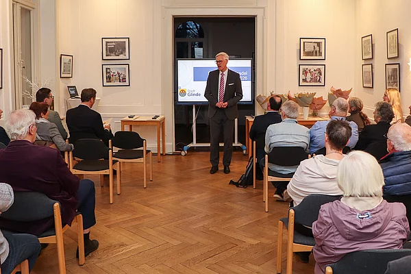 Bürgermeister Rainhard Zug spricht zu den Gästen. das Publikum schaut ihn an.