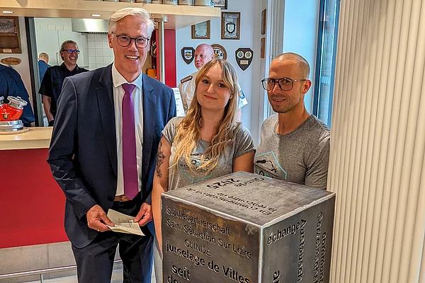 Bürgermeister Rainhard Zug neben einer Frau und einem Mann mit einer Würfelskluptur.