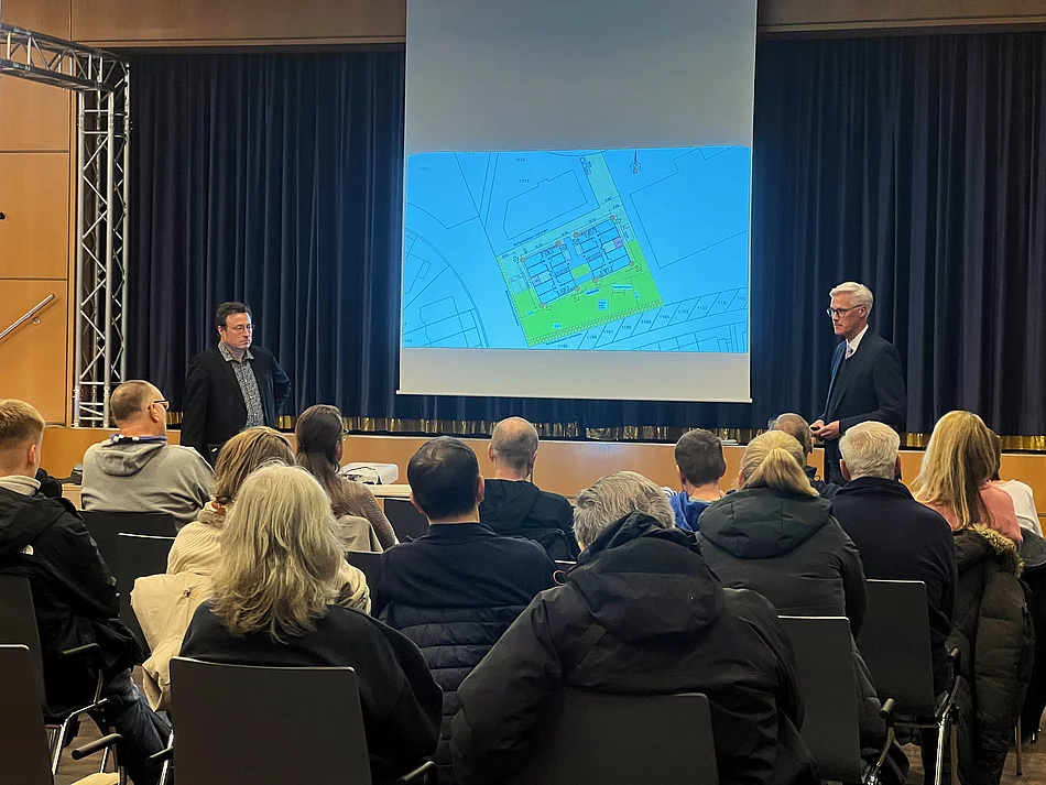 Publikum schaut auf eine Leinwand mit einem Bild eines Grundrisses