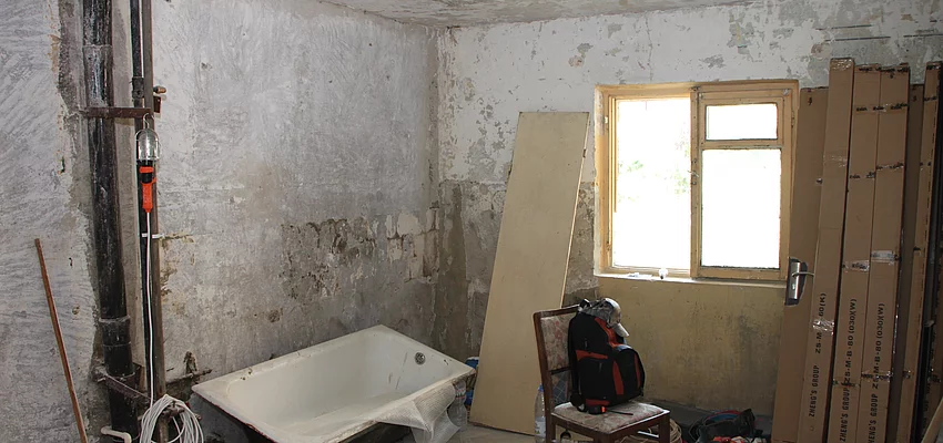 Ein Zimmer wird umgebaut. Leitungen sind zu sehen, die Wände sind unverputzt. Eine Badewanne steht im Raum.