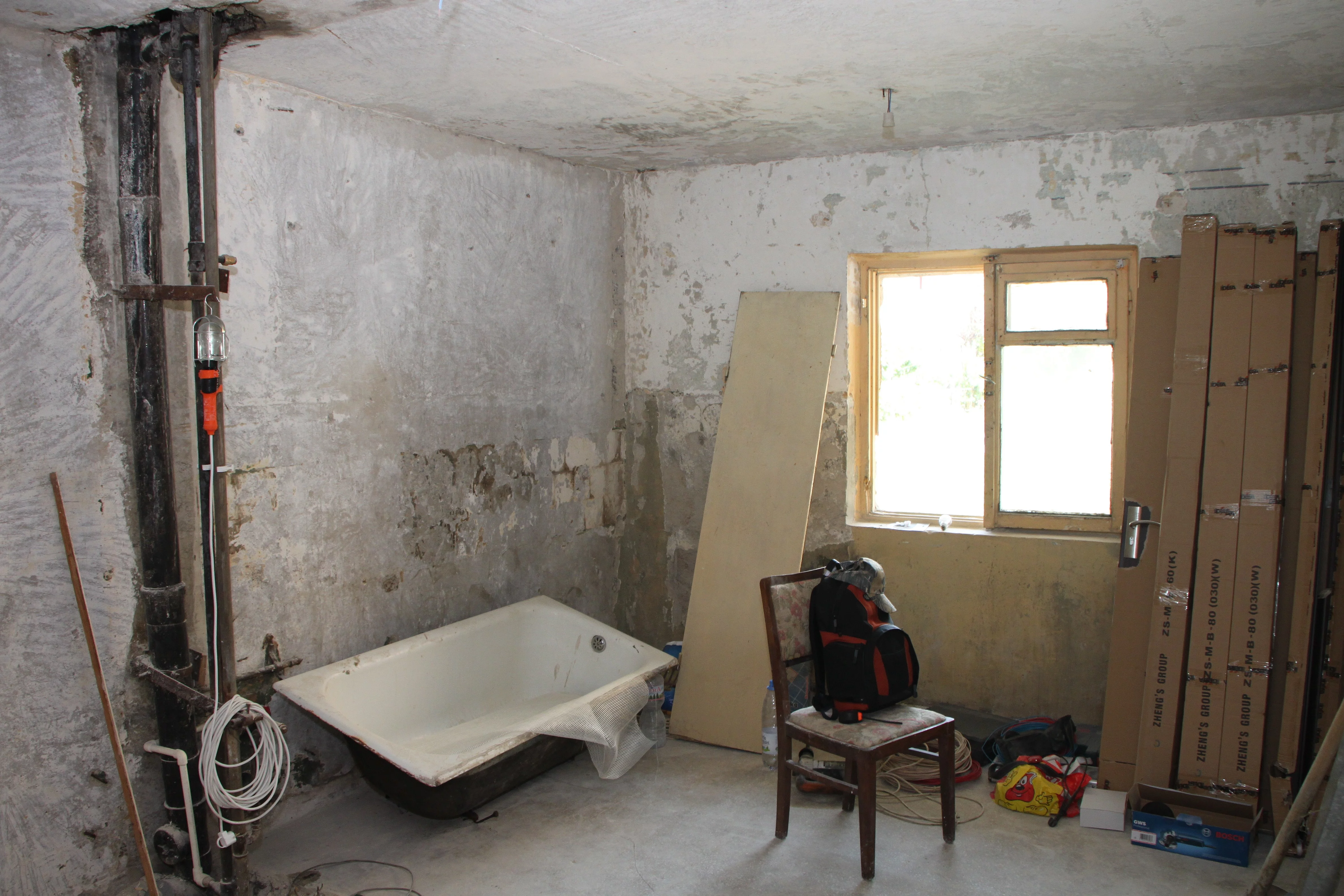 Ein Zimmer wird umgebaut. Leitungen sind zu sehen, die Wände sind unverputzt. Eine Badewanne steht im Raum.