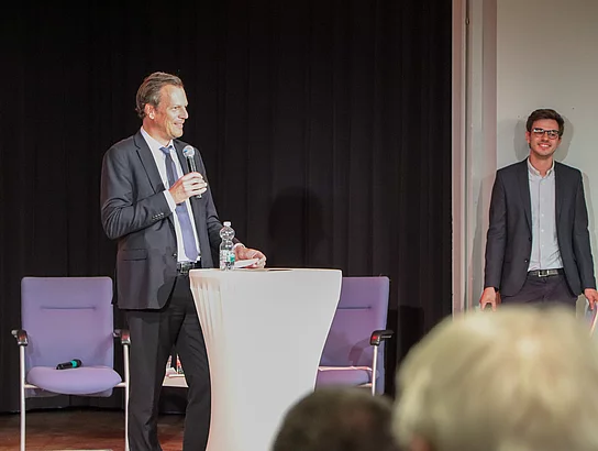 Bürgervorsteher Claus Peters steht an einem Tisch und hat ein Mikrofon in der Hand.