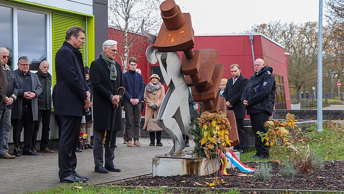 Menschen stehen am Mahnmal für das Zwangsarbeitslager Wiesenfeld.