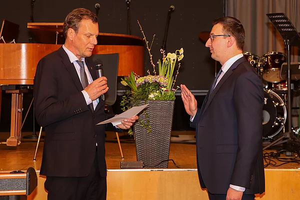 Bürgervorsteher Peters verliest einen Text während Patrick Klose die rechte Hand vor der Brust zum Eid erhoben hat.