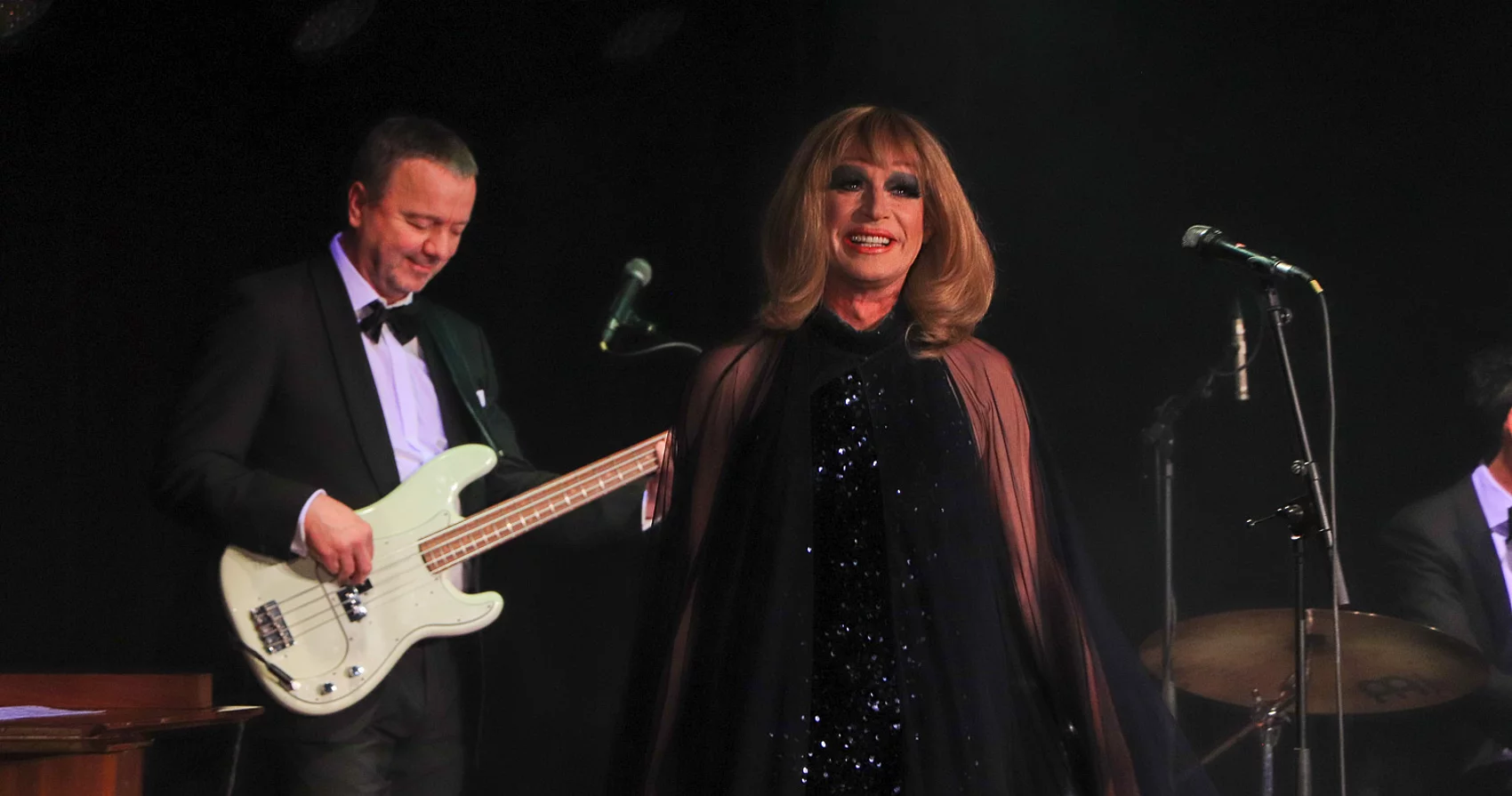 Tim Fischer geht zum Mikrofon. Im Hintergrund steht ein Mann mit einem Bass. 