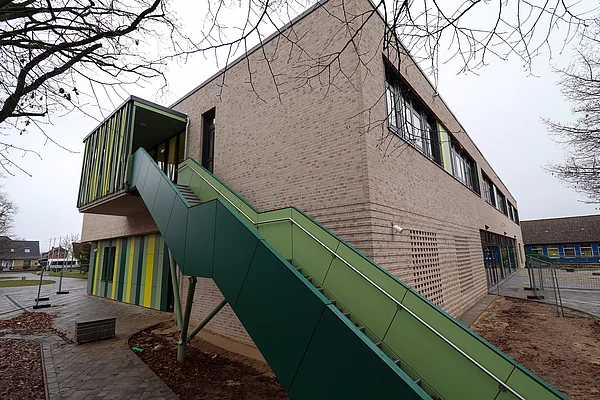 Eine grüne Treppe führt außen am Haus nach unten zum Pausenhof. 