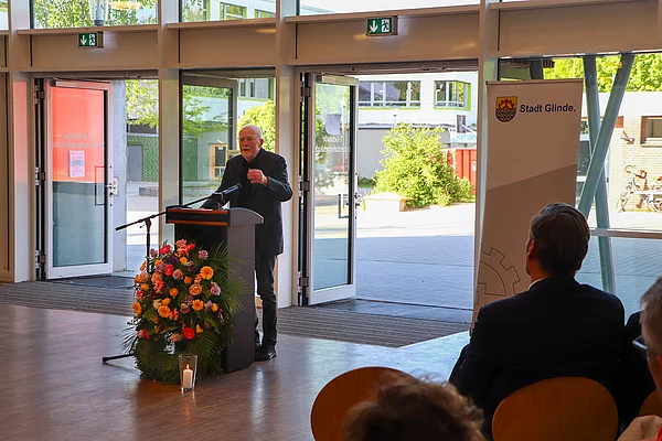 Ein alter Mann steht am Rednerpult. 