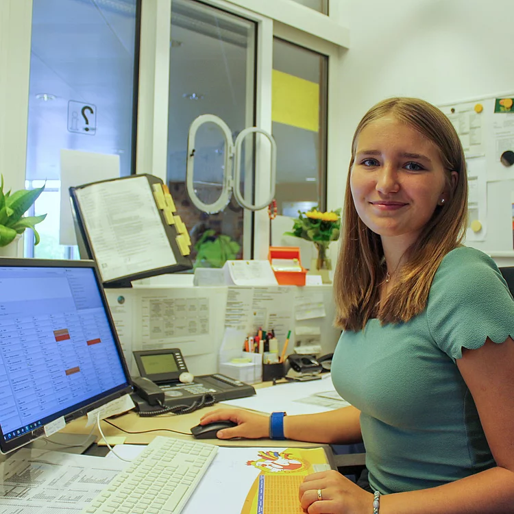 Praktikantin Aurelia Eisenberger an der Information Praktikantin Aurelia Eisenberger sitzt vor einem Computer Bildschirm