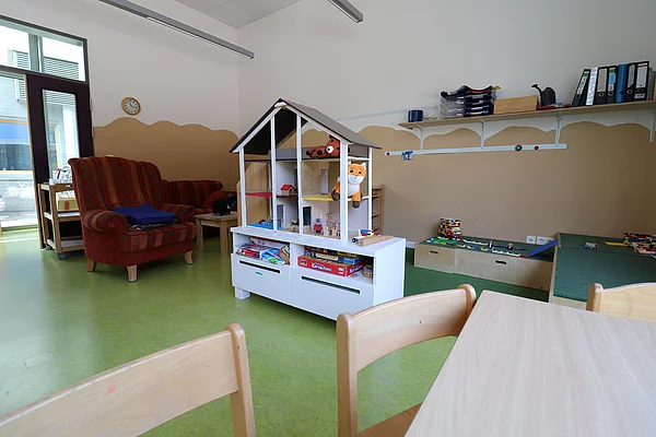 An einer Wand steht ein Puppenhaus in einem Hort-Gruppenraum.