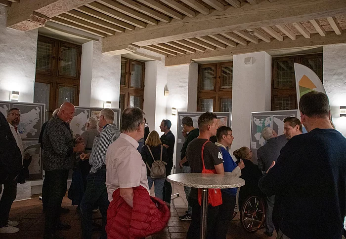 Menschen schauen auf Pinnwände mit Straßenkarten