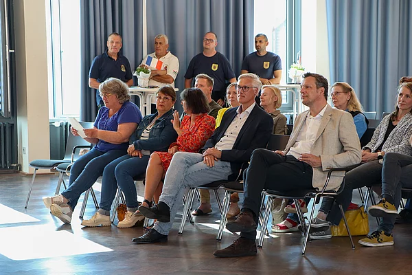 Menschen sitzen auf Stühlen und schauen auf eine Bühne.