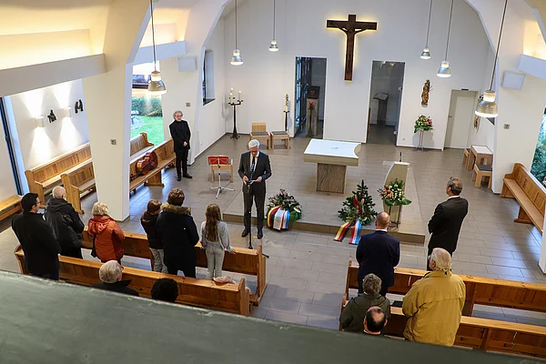 Bürgermeister Rainhard Zug verliest das Totengedenken, die Besucherinnen und Besucher stehen.